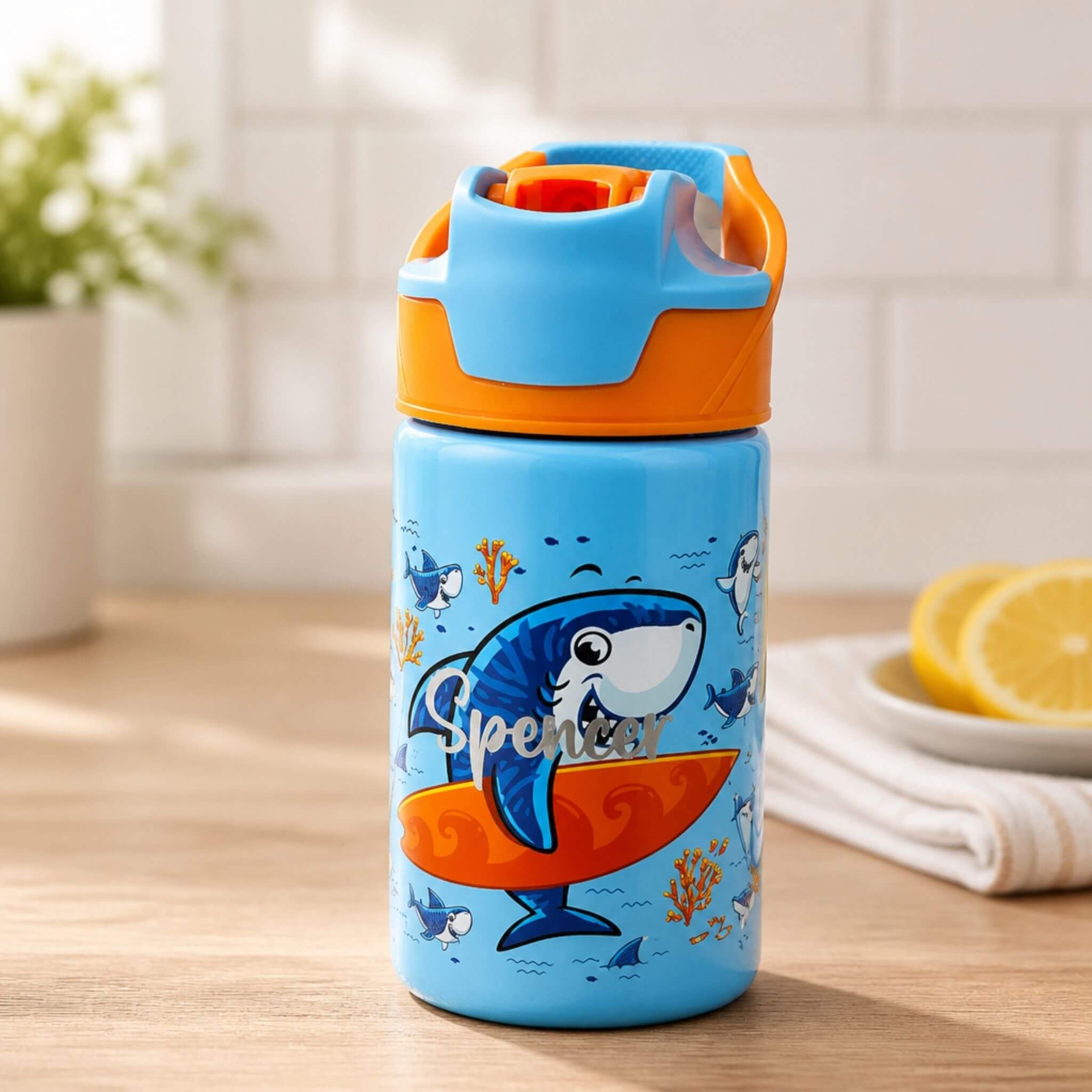 Personalised blue kids water bottle with orange lid, featuring a surfing shark design and the name "Spencer" — Little Cutlery Australia